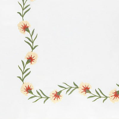 Close up of a napkin featuring a decorative floral border running along the left and bottom edges. The flowers are pale yellow to cream with red centers and green stems and leaves.