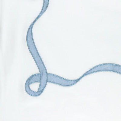 Close up of a napkin featuring a light blue satin ribbon tied in a loose knot