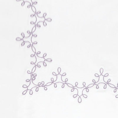 Close up of a napkin featuring a delicate lavender embroidered vine pattern along the left and bottom edges.