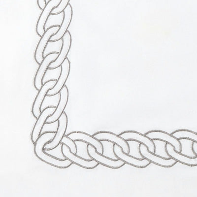 Close up of a napkin featuring a silver-toned metal chain link pattern forming an L-shape.