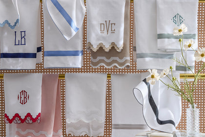 Monogrammed guest towels with colorful scalloped trim hanging on a rack