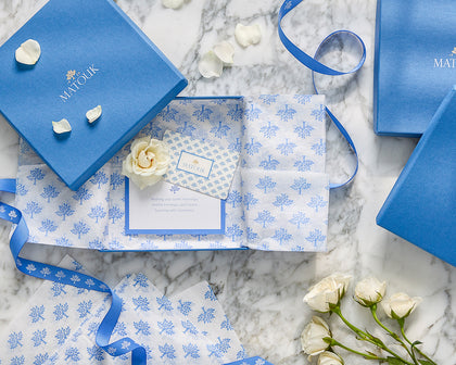 Matouk gift box wrapped with blue floral tissue paper and ribbon.