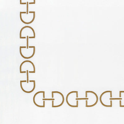 Close up of a napkin featuring gold metal chain trim with interlocking link shapes, shown along the top and left edges.