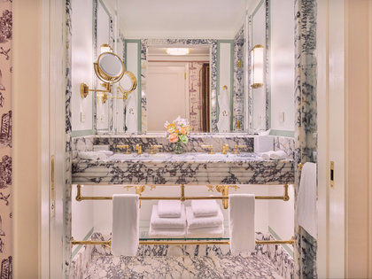 Luxury hotel bathroom with Calacatta Viola marble double vanity, brass fixtures and folded white towels