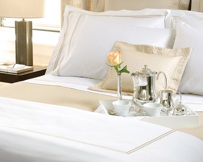 A room service tray atop a hotel bed with fine white linens. 