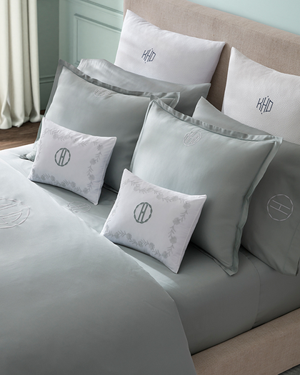 Bed dressed with monogrammed shams and pillows in varying sizes