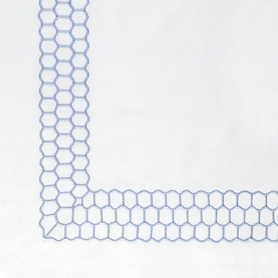 Close up of a napkin featuring a delicate light blue geometric border pattern along the edges.