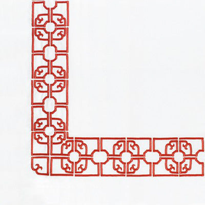 Close up of a napkin featuring red decorative corner tile with an ornate traditional lattice pattern