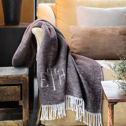 Fringed throw draped over a sofa with a block-letter monogram