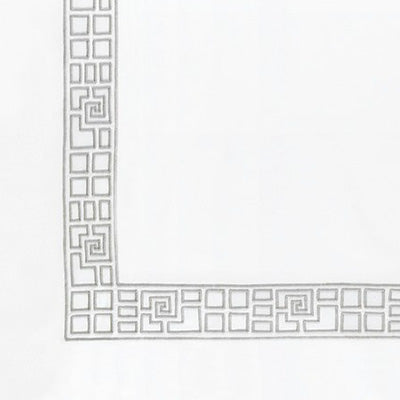 Close up of a napkin featuring a Greek key pattern border in gray outline.