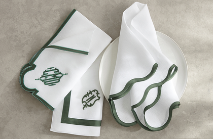 White napkins with green trim and a monogram on a table setting