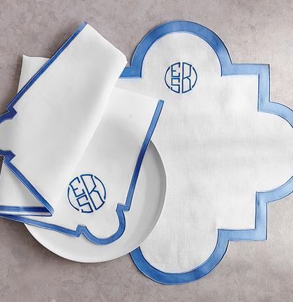 White scalloped napkins and placemat with blue trim and a monogram