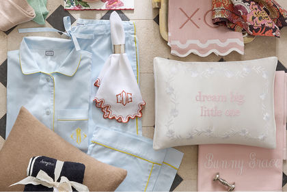 Gift flat lay with pajamas, a monogrammed washcloth, and a nursery pillow