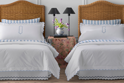 Twin beds with white scalloped bedding and blue trim in a kids' room
