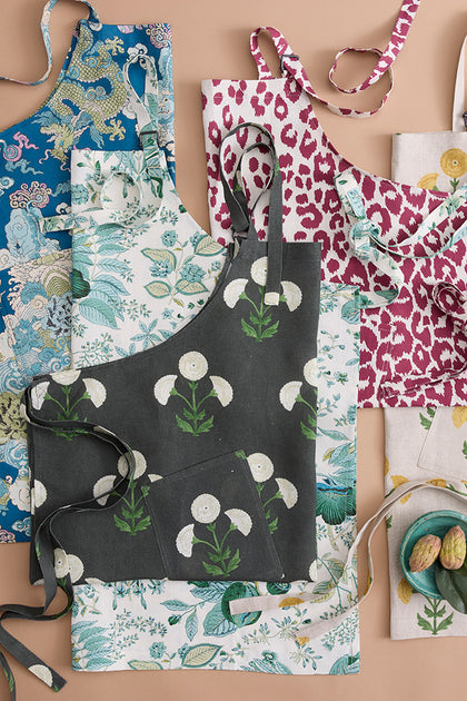 Schumacher aprons in assorted prints, laid flat.