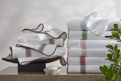 White Astor Braid towels with an embroidered trim, stacked.