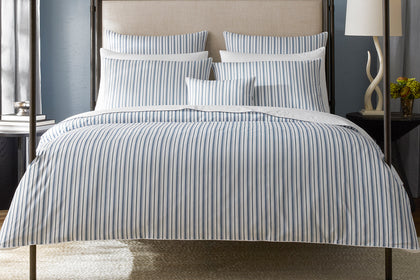 Navy striped Calypso bedding styled on a bed.