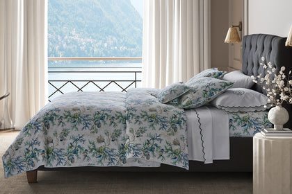 Del Tesoro floral bedding styled on a bed by a window.