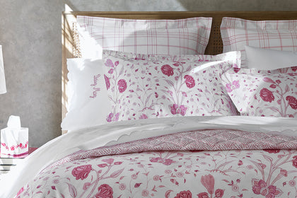 Pink floral Khilana bedding with a personalized pillow, styled on a bed.