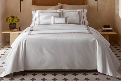 White Ophelia Pique bedding with an embroidered border, styled on a bed.