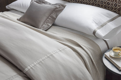 Gray bedding with a herringbone throw, styled on a bed.