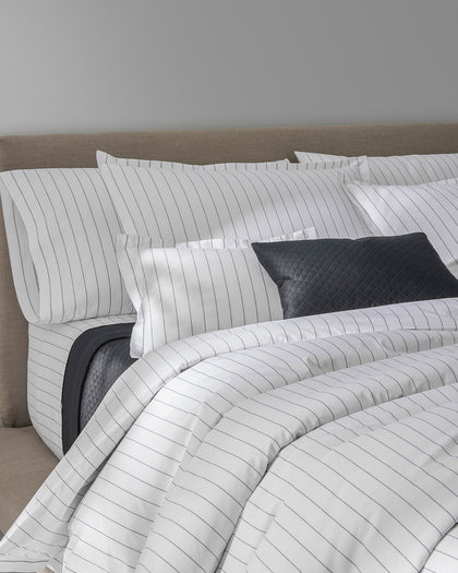 White Amalfi pinstripe bedding with a charcoal quilted accent pillow.