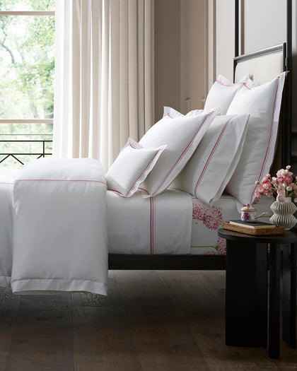 White Amara Triple Pearl sheets with pink triple-dot embroidered trim, styled on a bed.