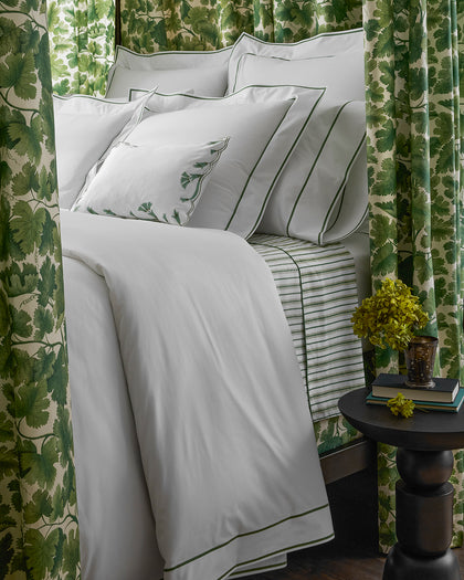 White Ansonia sheets with a green single-stripe trim, styled on a bed.