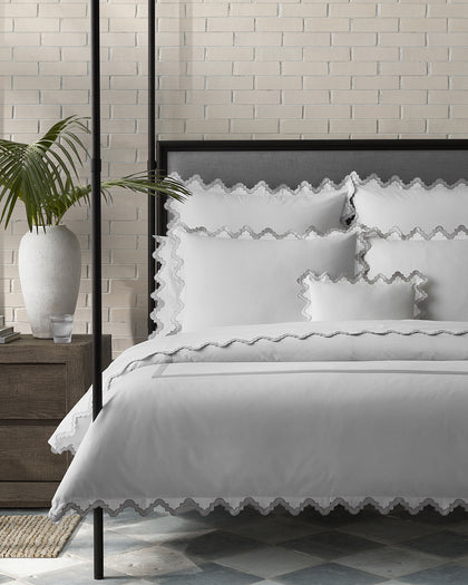 White Aziza bedding with wavy scalloped trim, styled on a bed.