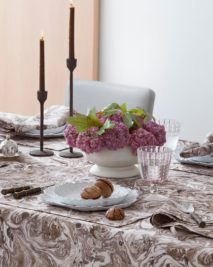 Balthazar marbled-print tablecloth in brown and taupe tones, set with candles and hydrangeas.