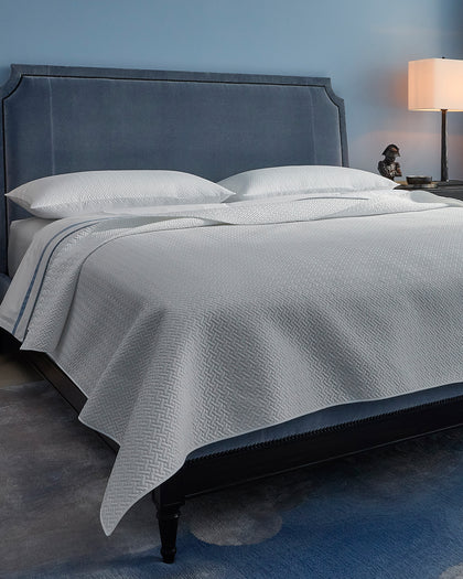 White Basketweave quilted bedding styled against a headboard.