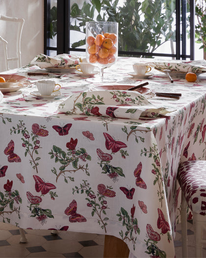 Baudin Butterfly print tablecloth with burgundy butterflies and florals, set with teacups and oranges.