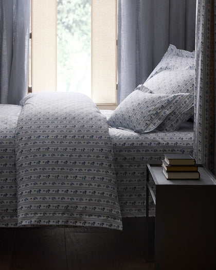 Blue and white striped floral Cabanon Stripe bedding, styled on a bed.