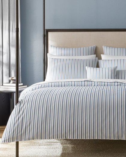 Blue and white striped Calypso bedding styled on a bed.