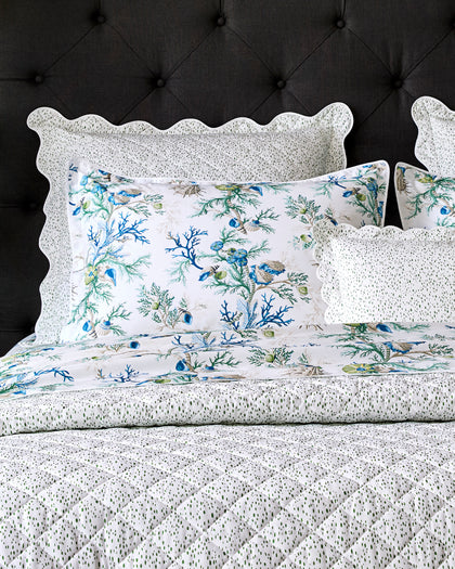 Celine speckled quilted bedding in white and green, layered with a coral and shell print pillow sham.