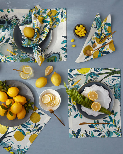 Citrus Garden print placemats and napkins with lemon trees, set with fresh lemons and lemonade from above.