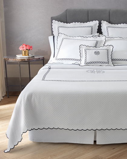 Classic Chain white matelassé bedding with a monogrammed pillow on a bed