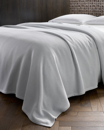 Gray textured Costa Mesa blanket draped over a bed.