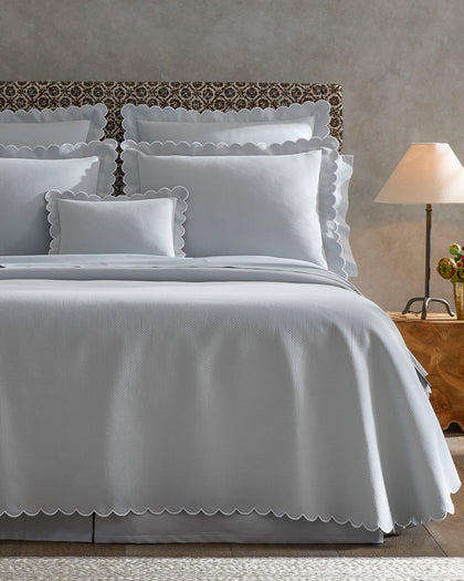 Pale blue Diamond Pique scalloped bedding styled against a headboard.