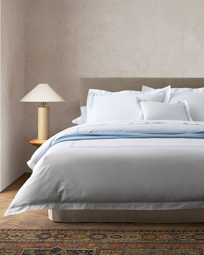 White Essex bedding with blue contrast stitching, layered with a blue throw.