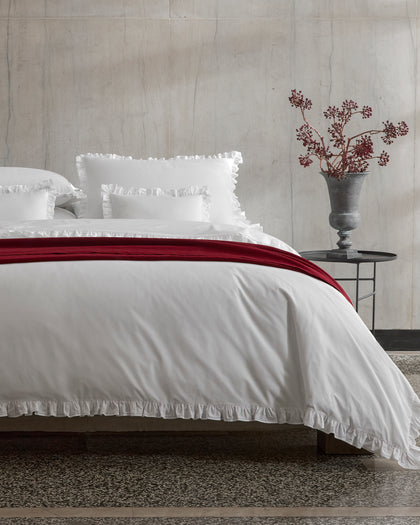 White Georgia ruffled bedding layered with a deep red velvet throw.