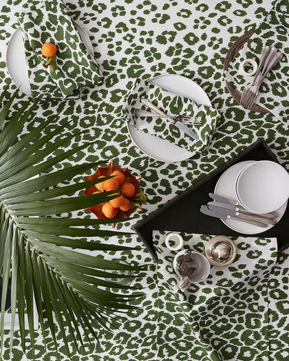 Green Iconic Leopard print tablecloth and napkins, set with white plates and apricots from above.