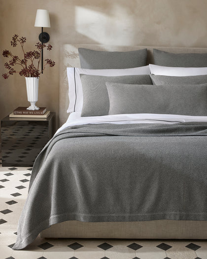 Black and white Jackson houndstooth-textured bedding layered with white piped sheets.