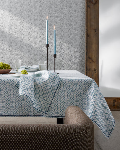 Blue and white Laksha medallion print tablecloth draped over a table beside blue candles.