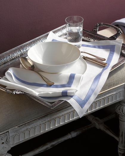 White Lowell placemat and napkin with a blue bordered trim, set on a tray.