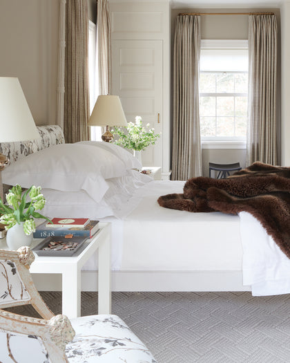 White Luca Hemstitch bedding layered with a brown faux fur throw.