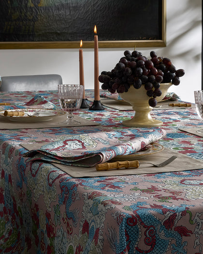 Magic Mountain dragon print tablecloth in blue and red, set with candles and black grapes.