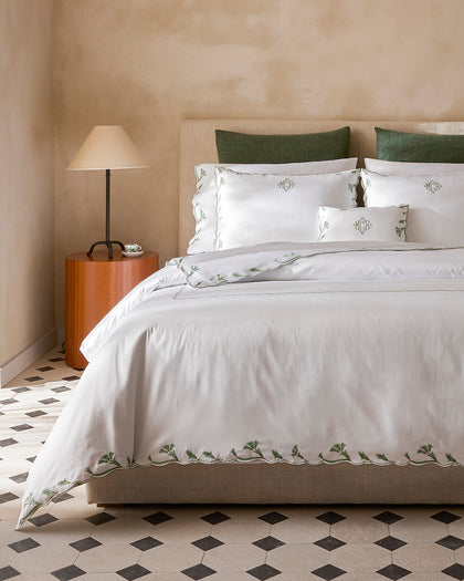 White Marcella monogrammed sheets with a green vine-embroidered scalloped trim.