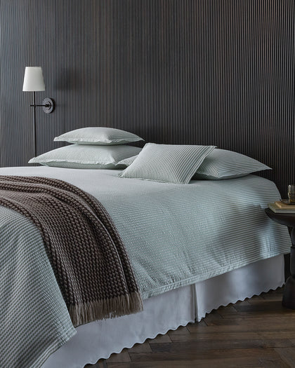 Green-striped Matteo bedding layered with a brown knit throw.