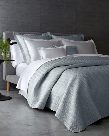 Gray herringbone-quilted Netto bedding styled on a bed.